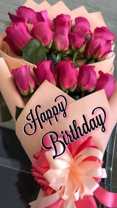 a bouquet of pink roses sitting on top of a table next to a sign that says happy birthday