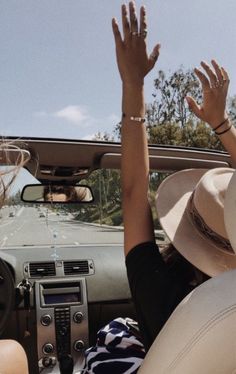 two people sitting in the back seat of a car with their hands up to the sky