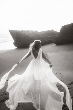 a woman in a white dress is walking on the beach