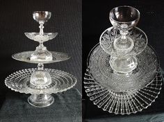 three clear glass dishes and two silver candlesticks on a black clothed surface