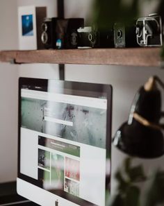 a computer monitor sitting on top of a desk next to a potted green plant