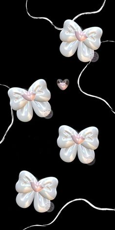 three white bows with pearls attached to them on a black background, one is tied up and the other two are made out of plastic