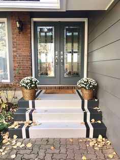 two baskets with flowers sit on the front steps of a brick house, next to an entry way