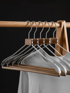 a wooden hanger with six white shirts hanging from it's sides and four pairs of pants on them