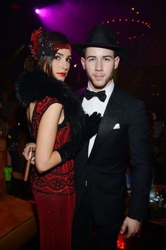 a man in a black hat and woman in a red dress standing next to each other