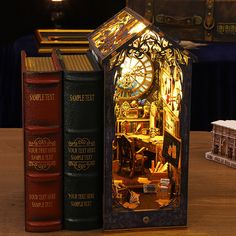 an illuminated clock in the middle of three books on a table next to each other