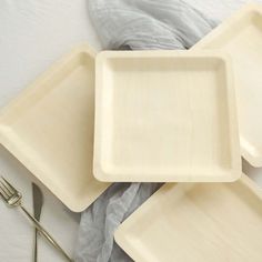 three empty trays sitting on top of each other next to forks and spoons