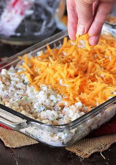 a person dipping cheese into a casserole dish