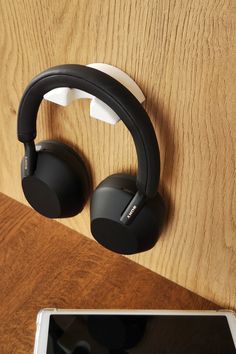 an electronic device and headphones on a wooden surface next to a tablet computer screen