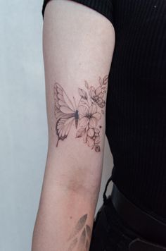 a woman's arm with a butterfly and flowers tattoo on the left side of her arm