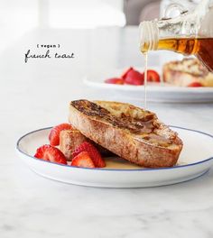 a piece of toast on a plate with strawberries and syrup being drizzled over it