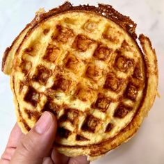 a person holding up a waffle on top of a table