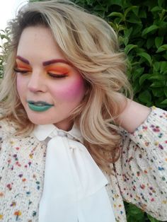 a woman with colorful makeup is posing for the camera