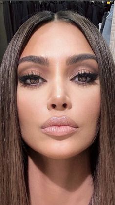 a woman with long brown hair and makeup looks at the camera while she is wearing black eyeliners