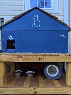 a dog house built into the back of a wooden pallet with two bowls on it