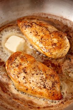 two pieces of chicken in a pan with butter