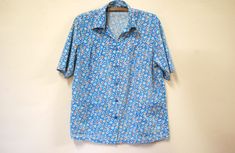 "FREE SHIPPING WORLDWIDE FOR ALL ADDITIONAL ITEMS PURCHASED  -1980s vintage blue carnation floral smock shirt -Will fit numerous sizes, oversized on an XS -Button down closure -2 front deep apron style pockets -Lightweight loose airy cotton blend fabric MEASUREMENTS:  - Length: 67cm (26.5\") - Bust: 57cm (22.5\") - Waist: 56cm (22\") Material: Cotton/Polyester blend Estimated fit: XS-M Condition: Excellent vintage Measurements taken while garment is laying flat x2 for full circumference. Check the measurements before purchasing. Your item will be sent within 1 business day.♡" Smock Shirt, Blue Carnations, Flower Print Blouse, Black Sheer Blouse, Smock Blouse, Chiffon Shorts, Hipster Shirts, Sleeveless Tee, Beautiful Skirts