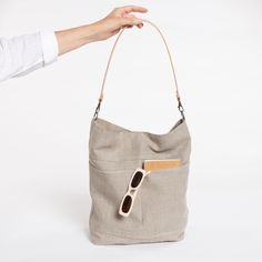 Large linen bag with exterior pockets and a wide leather strap. Handmade with a very light beige rustic linen. It is a bag with a large capacity but lightweigt, designed to go to work, school and for day to day. With a timeless minimalist style. The bag is lined with cotton fabric, two inside pockets, one of them with a zipper. It closes with a zipper (not with a magnet as you see in the photo)and double outside pocket. Removable wide leather strap available in 3 colours. By removing the strap, Canvas Bucket Bag Tote With Pockets, Canvas Bucket Tote Bag With Pockets, On-the-go Natural Hobo Shoulder Bag, Everyday Beige Bucket Bag With Pockets, Neutral Hobo Tote Bag With Leather Handles, Versatile Beige Hobo Bag With Leather Handles, Neutral Hobo Bag With Leather Handles Tote Shape, Everyday Bucket Shoulder Bag With Canvas Lining, Neutral Hobo Bag With Adjustable Strap For Everyday Use