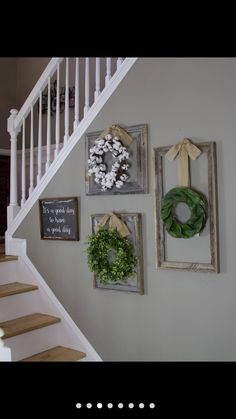 three framed pictures hang on the wall next to a stair case with wreaths and other decorations