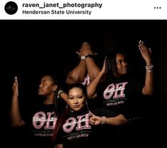 three women in black t - shirts with pink letters on them and one woman holding her hands up