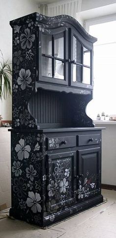 an ornate black china cabinet with flowers painted on the front and sides, in a kitchen