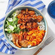 a bowl filled with rice, meat and vegetables on top of a blue striped towel