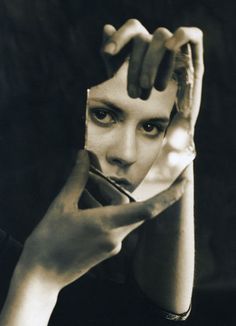 a black and white photo of a woman holding her hands up to her face with one hand