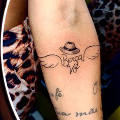 a person with a hat and wings tattoo on their arm