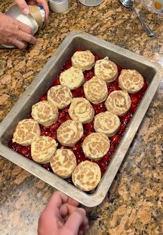 a pan filled with food sitting on top of a counter next to a person's hand