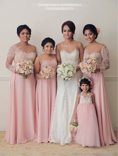 a group of women standing next to each other wearing dresses and holding bouquets in their hands