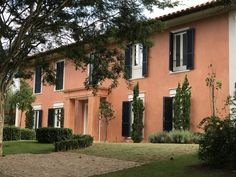 an orange house with black shutters and trees