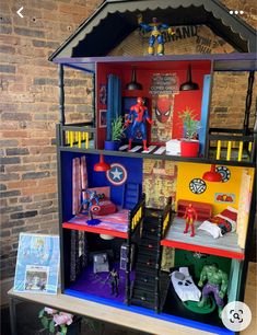 a doll house is on display in front of a brick wall and table with toys