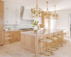 a large kitchen with marble counter tops and gold barstools, surrounded by wooden cabinets