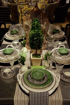 the table is set with green dishes and place settings for two people to sit at