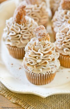 cupcakes with cream cheese frosting are on a white plate and the words, churro cupcakes