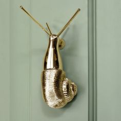 a gold snail shaped hook on a green door