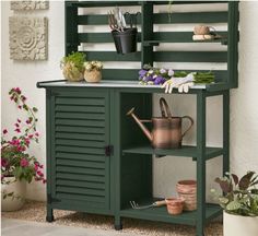 an outdoor potting bench with plants and pots on it, in front of a white wall