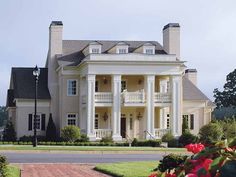 a large white house sitting on top of a lush green field