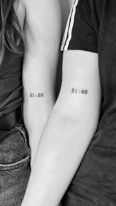 two people sitting next to each other with numbers tattooed on their arm and the number twenty