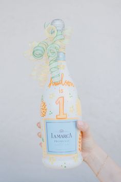 a hand holding up a bottle of champagne with the number one on it's label