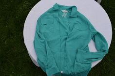 "Vintage women`s emerald green blouse with 2 chest pockets and decorative sides splits on the bottom. Polyester long sleeve button up shirt. brand: Jumper (United Kingdom) labeled material: 100% polyester condition: great unused vintage. Without damages. 1 original spare button in plastic package for sewn up - never been 1 frontal button. Labeled size: S EU (S), ESTIMATED size is \"L\". The women model (at the photos), has S/M size. measurements in lying flat: length on the back 75 cm / 29.3\" i Green Fall Blouse With Pockets, Green Blouse With Pockets For Fall, Green Long Sleeve Blouse With Button Closure, Emerald Green Blouse, Long Sleeve Button Up Shirt, Vintage Women, Green Blouse, Shirt Brand, Label Sizes