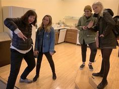 three girls are standing in the middle of a room and one girl is pointing at something