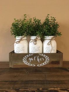 three mason jars with greenery in them sitting on a table