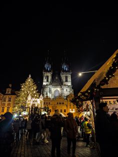 people are walking around in front of a christmas tree at the old town square, prague