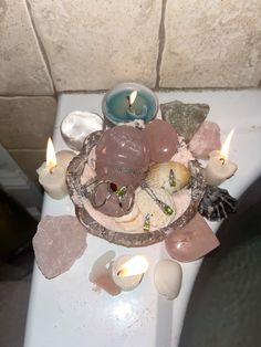 a white toilet with candles and rocks on it