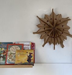 there is a book shelf with books on it and a paper sunburst hanging from the wall