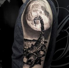 a man's arm with a scorpion on it and the moon in the background