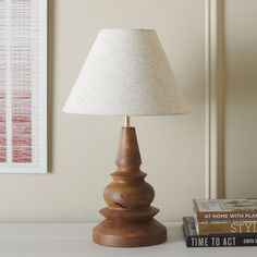 a lamp sitting on top of a table next to a stack of books and a book