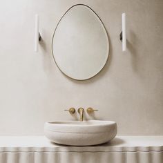 a white sink sitting under a round mirror next to a wall mounted faucet