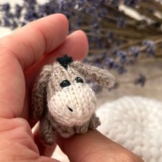 a tiny stuffed animal is held in someone's hand next to some lavenders